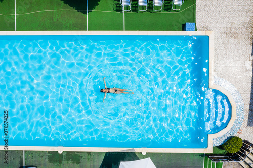 Aerial top view of woman in swimming pool water from above  tropical vacation concept