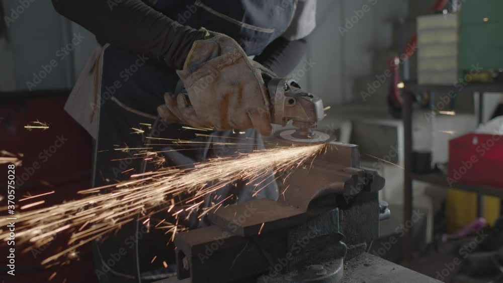 Hand of a worker while Grinding metal and orange flying sparks Hand of a worker while Grinding metal and orange flying sparks
