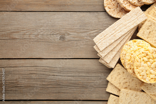 Various types of healthy whole grain crispbreads on grey wooden background.