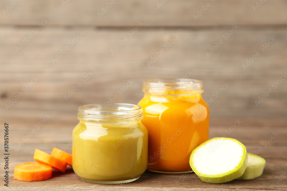 Glass jars with nutrient baby food on grey wooden background Glass jars with nutrient baby food on grey wooden background