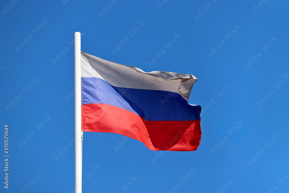 Russian flag waving against the clear blue sky. Symbol of Russia, russian authority concept Russian flag waving against the clear blue sky. Symbol of Russia, russian authority concept