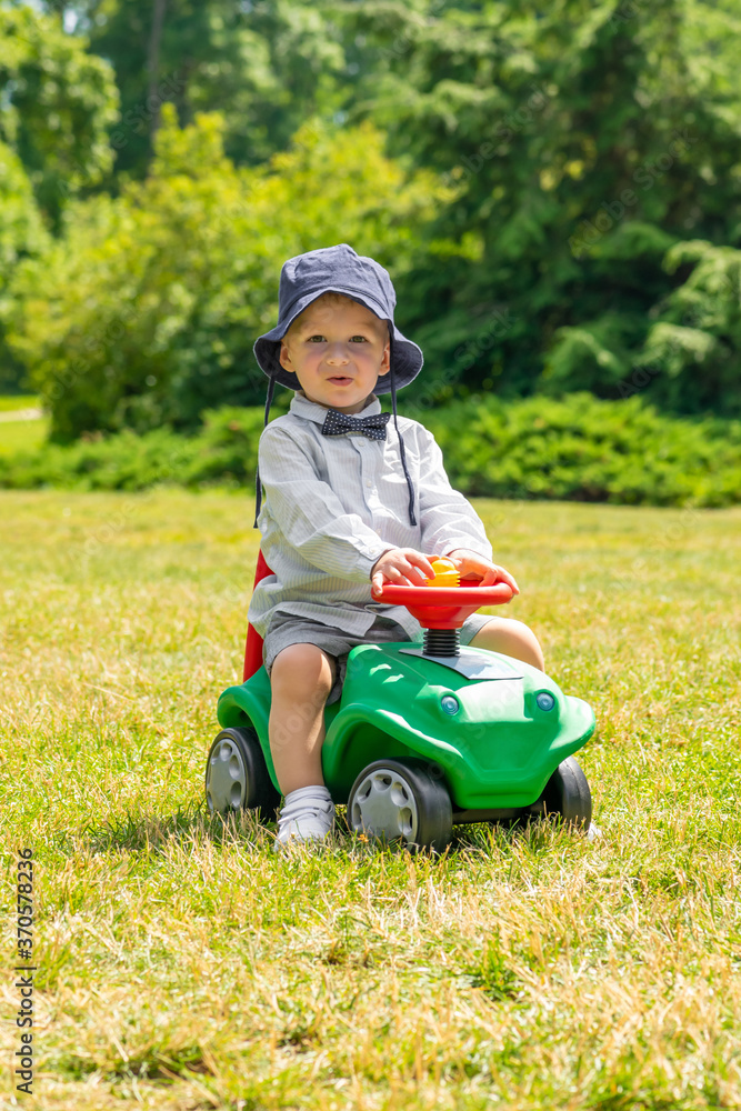 Child playing on green car on green meadow with copy space during sunny summer day Child playing on green car on green meadow with copy space during sunny summer day