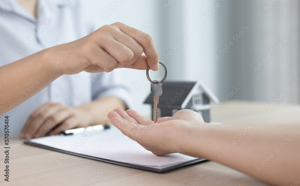 House salesman asks the customer to sign a house purchase contract and around the house with the keys. House salesman asks the customer to sign a house purchase contract and around the house with the keys.