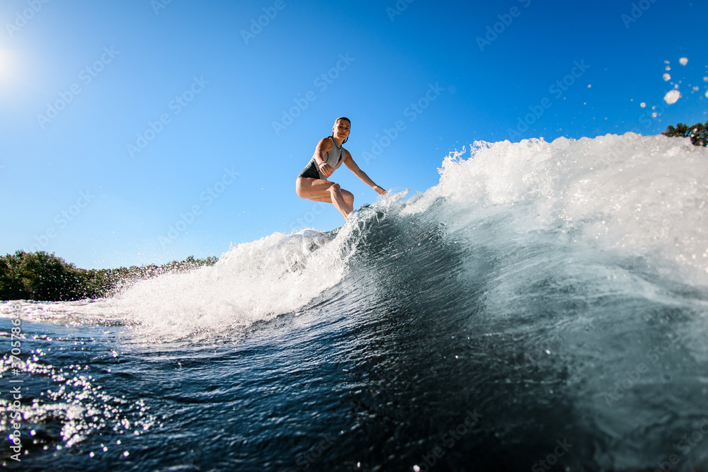active young woman masterfully rides the wave on surfboard