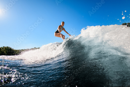 active young woman masterfully rides the wave on surfboard