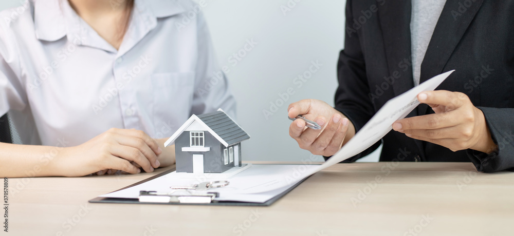 House salesman asks the customer to sign a house purchase contract and around the house with the keys.