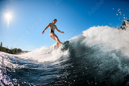 active young wet woman masterfully rides the wave on surfboard