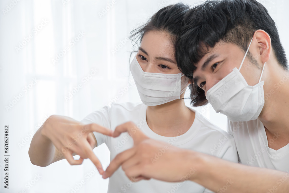 Asian couple wearing protective face mask and making shape of Heart by their Hands at home. Asian couple wearing protective face mask and making shape of Heart by their Hands at home.