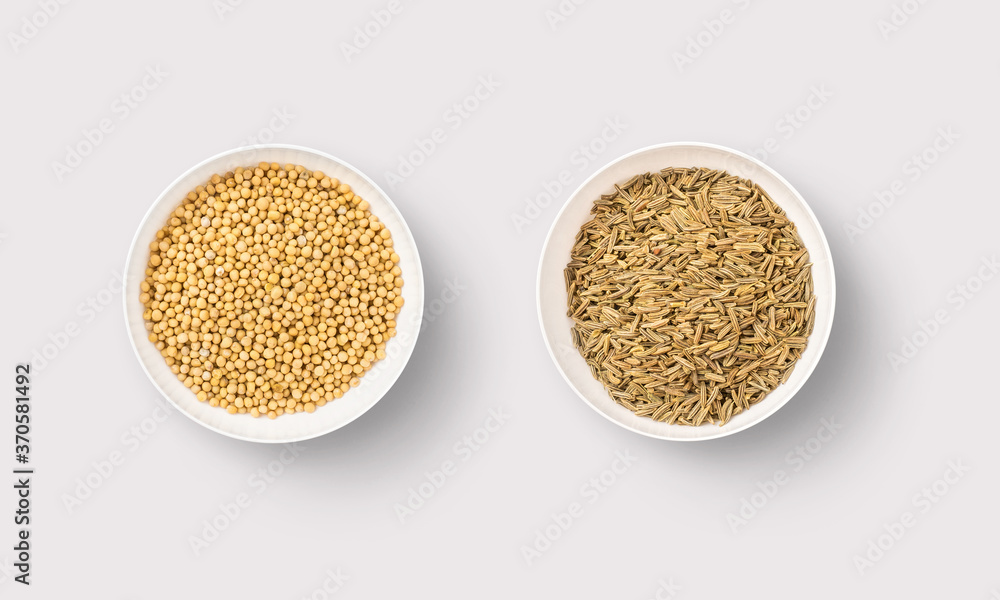Cumin and mustard seeds in white bowls on a white background Cumin and mustard seeds in white bowls on a white background