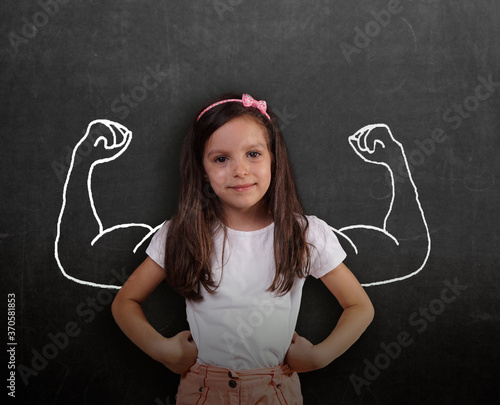 little girl standing against chalkboard and strong winner concept