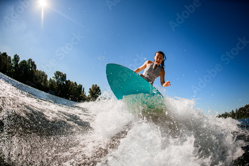 view of athlete woman in gray swimsuit who jumps with bright surf board.