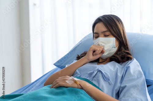 Woman patient wearing face mask and recuperating while sleeping on a hospital bed.