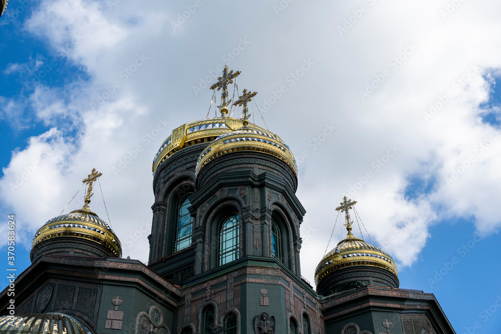 panoramic view of a dark temple with golden domes against a background of gray clouds