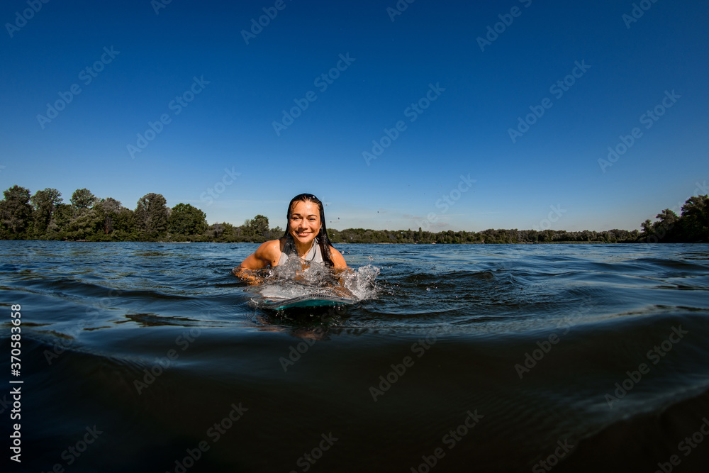 young woman with brown hair floats on the river on wakesurf board young woman with brown hair floats on the river on wakesurf board