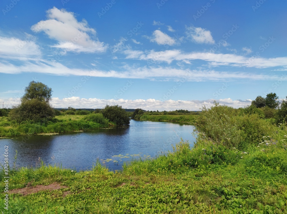 blue sky with beautiful clouds above the river among the green field