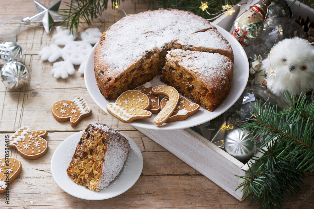 Traditional Christmas fruitcake on the background of a box with Christmas toys and fir branches.
