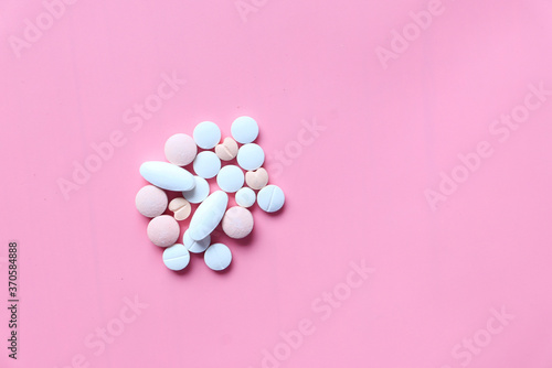 top view of pills spilling on pink background 