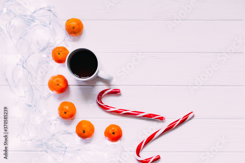 Christmas garlands, tangerine, candies on white wooden surface. top view.