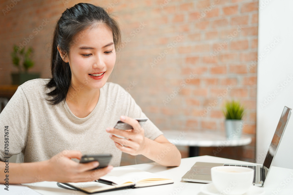 Asian young woman order food and shopping online make payment by credit card on computer and smartphone while quarantine at home from coronavirus covid-19 as new lifestyle Asian young woman order food and shopping online make payment by credit card on computer and smartphone while quarantine at home from coronavirus covid-19 as new lifestyle
