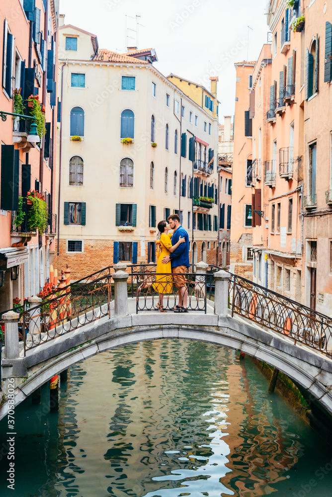 couple standing on the bridge crossing venice canals