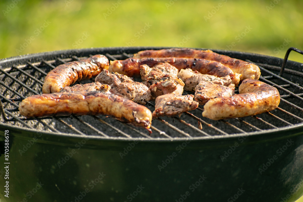 Grilling pig meat and sausages for a campfire party.