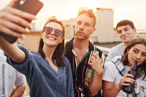 Taking selfie. Beautiful sunshine. Group of young people in casual clothes have a party at rooftop together at daytime