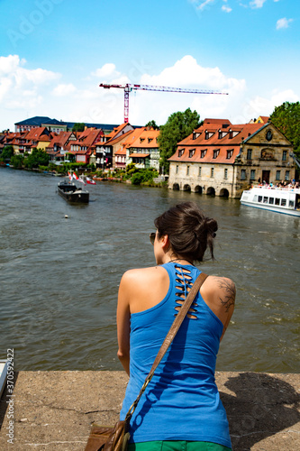 Bamberg, Germany;  young woman siting on a bridge ofer the river Regnitz as it flows through Bamberg, Germany. It is a UNESCO World Heritage Site photo