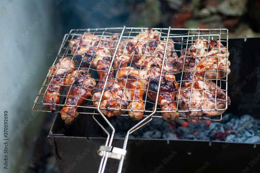 Appetizing chicken legs are grilled on wooden wood, although not very healthy food because it is fried but very tasty. Selective focus