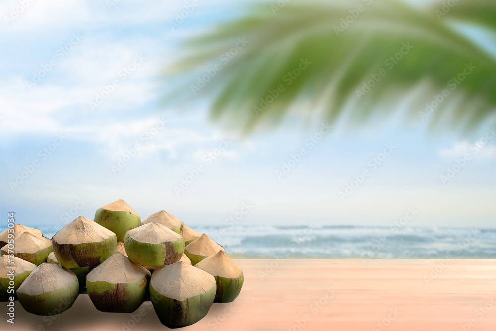 coconut on wood table countertop with softfocus palm and summer beach background