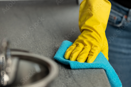 Vászonkép Woman's hands in yellow gloves cleaning counter top in kitchen