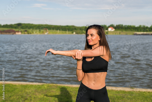 Portrait of a fitness woman doing warm up exercises outdoors in park