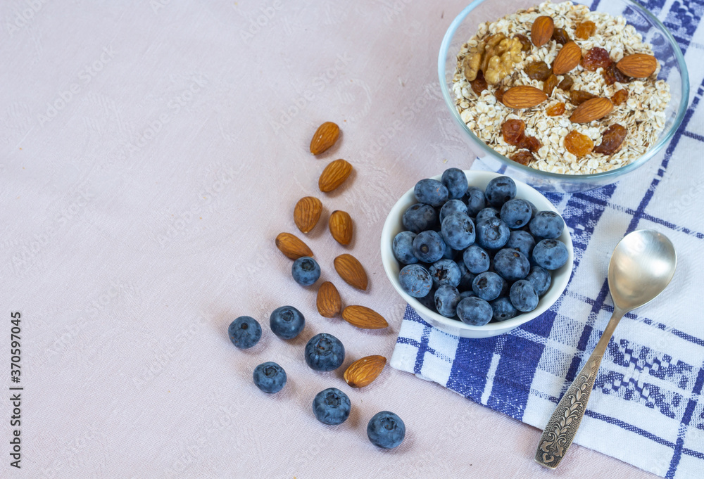 Bowls of granola, raisins, nuts and blueberries. Healthy breakfast every day. Copy space. Beige linen background. Flat lay Bowls of granola, raisins, nuts and blueberries. Healthy breakfast every day. Copy space. Beige linen background. Flat lay