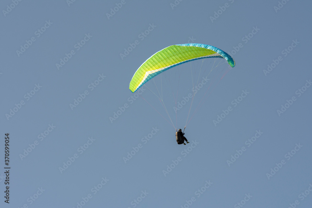 Persona vuela en parapente sobre el cielo azul
