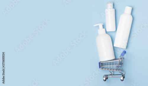 White cosmetic jars lie in a shopping basket. Online home shopping. Purchase of disinfection, laundry and care products.
