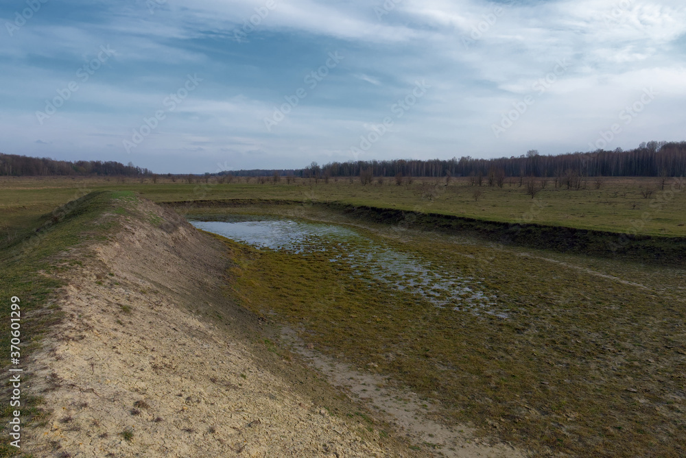 The exposed bottom of a dry pond. A shallow water body. The exposed bottom of a dry pond. A shallow water body.