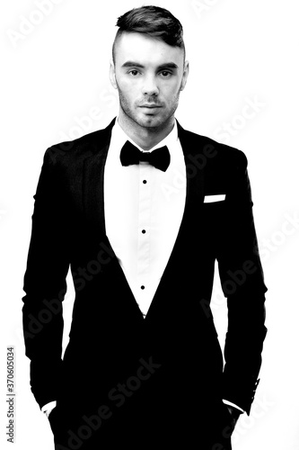 Obraz na płótnie A young male brunette in a strict tuxedo suit with a bow tie