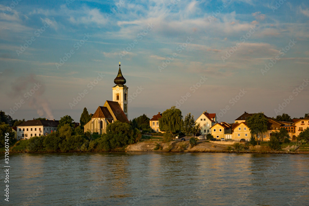 A church with clock tower along the Danube river near Sausenstein, Austria,