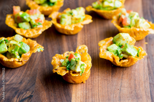 Spicy Guacamole served in crispy taco shells with salsas, cilantro and lime. Avocados diced and mixed with lemon and lime juices. Classic Tex-Mex, Mexican or American restaurant appetizer favorite.