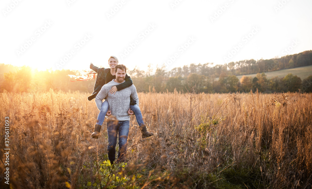 Young couple in love on a walk in autumn forest, holding hand ribbon kites.