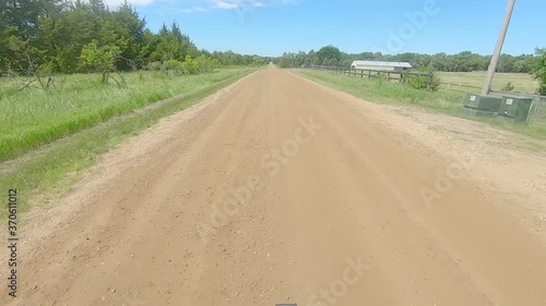 POV out the rear window driving on gravel road in the countryside of South Dakota; driving past pastures and over a river photo