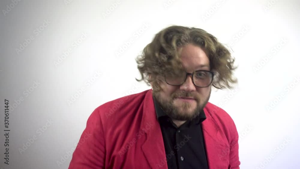 A young bearded man in a red suit is actively gesticulating with his hands.Close up of young adult man full of fury, looking at the camera.White background. A young bearded man in a red suit is actively gesticulating with his hands.Close up of young adult man full of fury, looking at the camera.White background.