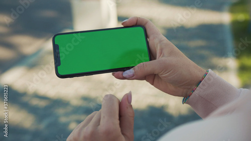 NEW YORK - 5 April 2018: Close up of woman hands holding and touching phone with green screen horizontal in the street sunlight car background internet technology business message slow motion