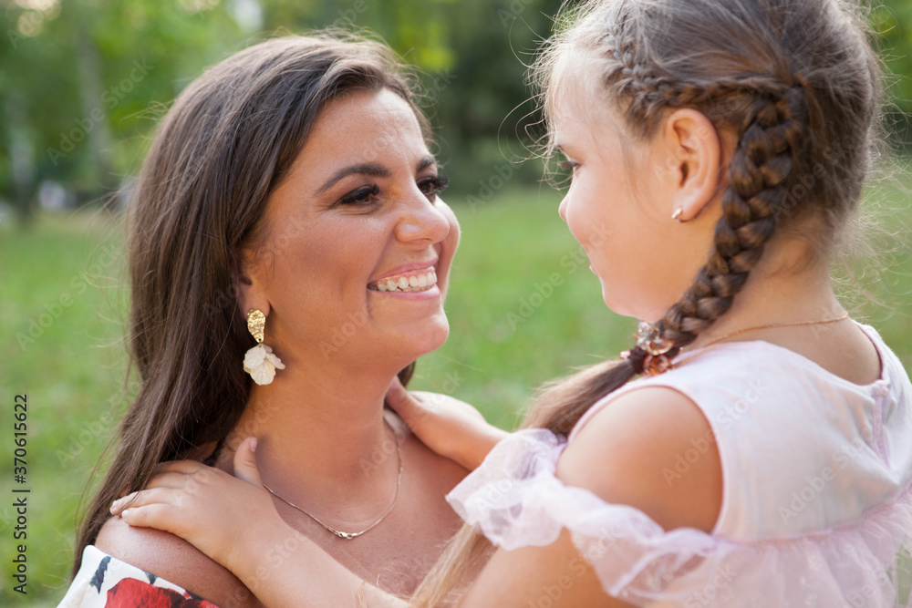 Close up of a happy beautiful woman smiling at her adorable little daughter outdoor at the park Close up of a happy beautiful woman smiling at her adorable little daughter outdoor at the park