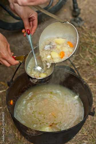 Fish soup is cooked on the fire. Ears in an iron bowl in nature.
