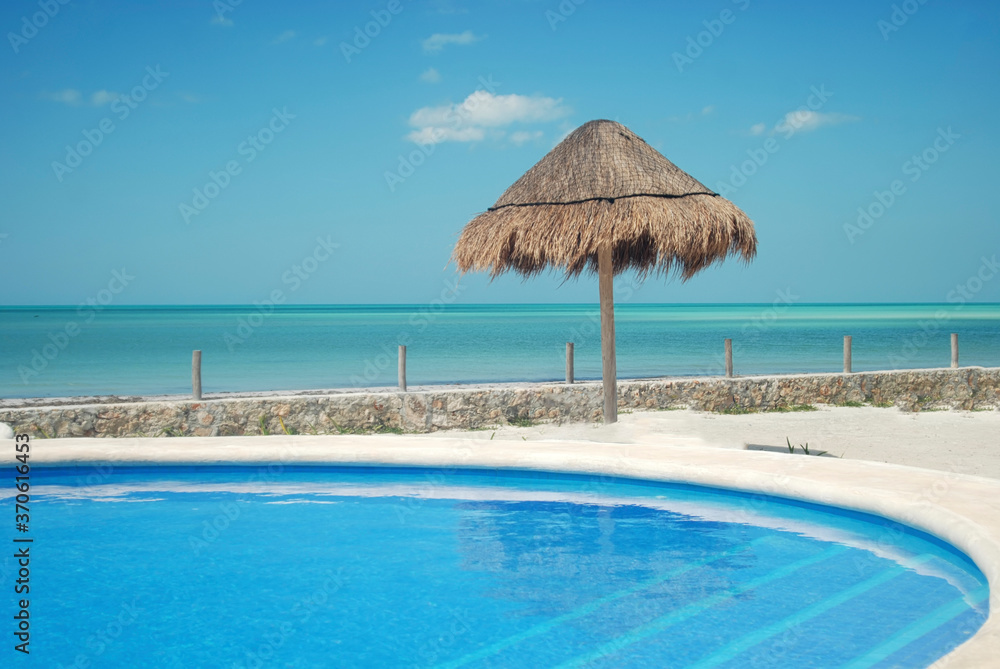Reed Beach Umbrella Creating Shade On A Beach near the pool oceanfront, Holbox island, Mexican Caribbean