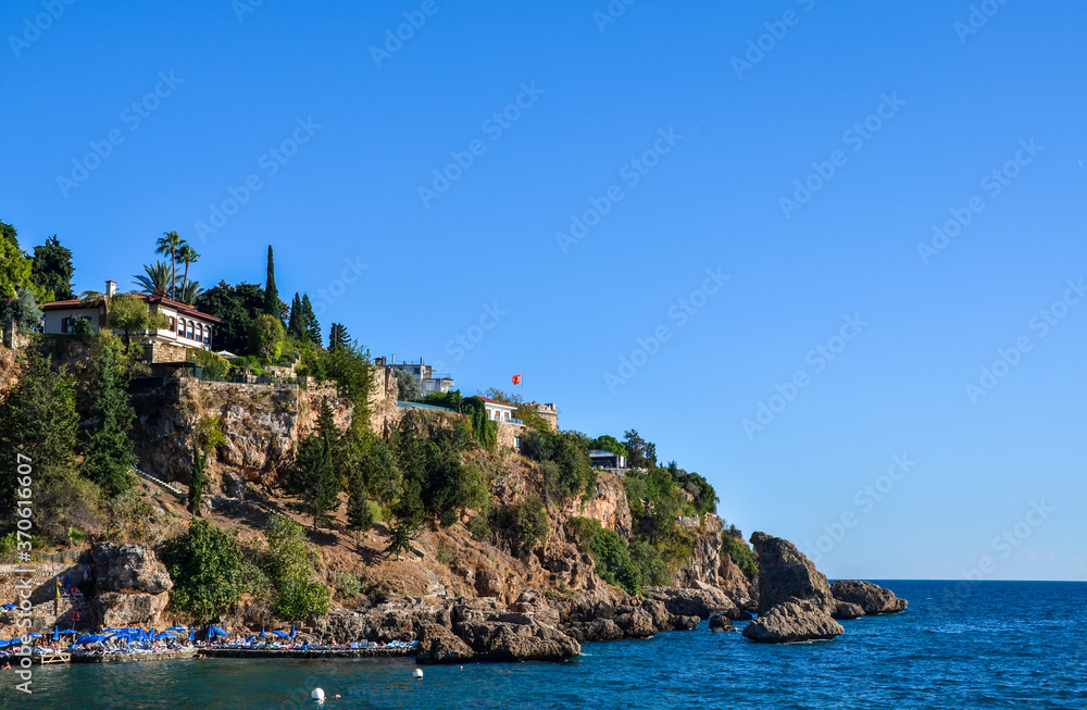 Coast stone embankment with tall cliff and Mermerli Beach in Kaleici district, Antalya, Turkey
