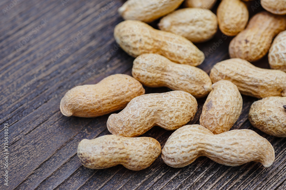 peanut grain in peel on wooden background peanut grain in peel on wooden background