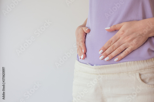 Pregnant woman in the early stages touches the belly with her hands. First and second trimester of pregnancy
