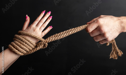 woman hands tied with a coarse rope close-up black background