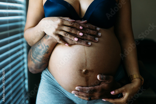 Black couples hands around belly in third trimester pregnancy